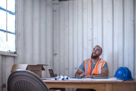 Builder sitting at desk in portable cabinの写真素材