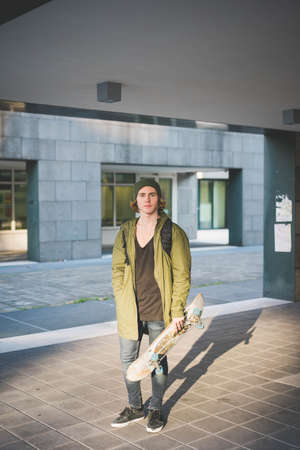 Portrait of cool young male urban skateboarder holding skateboardの写真素材