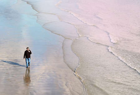 High angle front view of mature man walking on beach along coastline