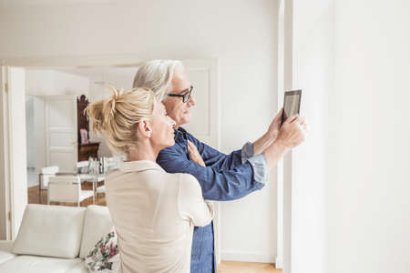 Couple taking self portrait, using digital tabletの写真素材