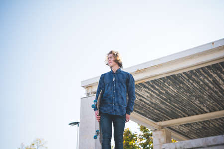 Portrait of young male urban skateboarder holding skateboardの写真素材