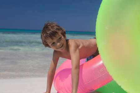 Boy playing on inflatable rings at beach, Majorca, Spainの写真素材