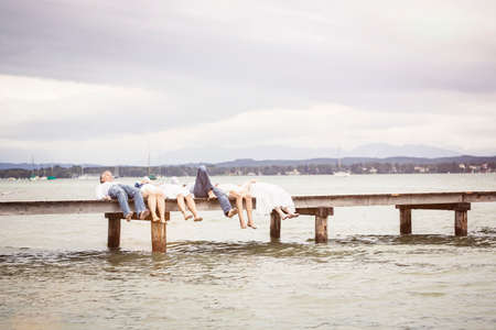 Group of friends lying in a row on pierの写真素材