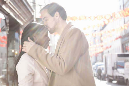 Couple standing in street, man kissing woman on headの写真素材