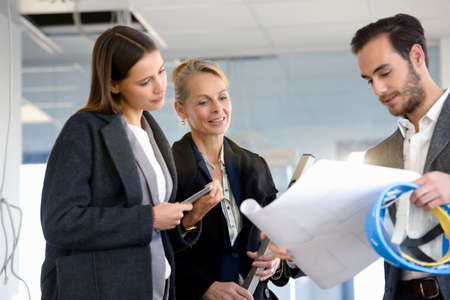 Architect and businesswomen looking at blueprint in new office