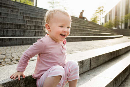 Baby girl, sitting on steps, laughing, outdoors