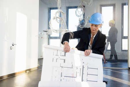 Businesswoman rolling blueprint in new office