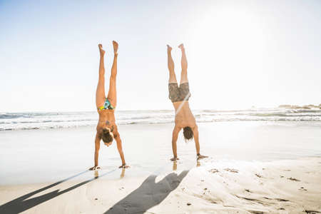 Mid adult couple doing handstands on beach, Cape Town, South Africaの写真素材