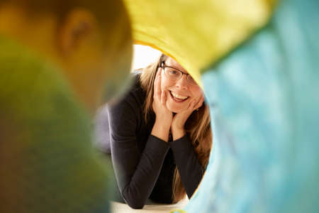Over shoulder view of baby girl crawling in multi-colour tunnel to mother