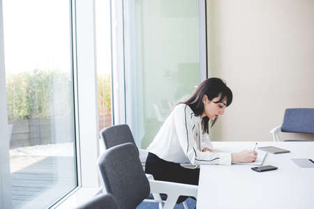 Young businesswoman writing notes at office deskの写真素材