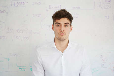 Man in front of white board looking at camera