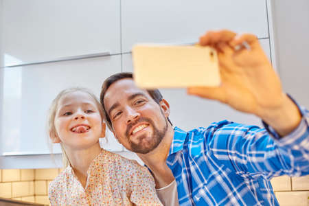 Father and daughter taking selfie in kitchenの写真素材
