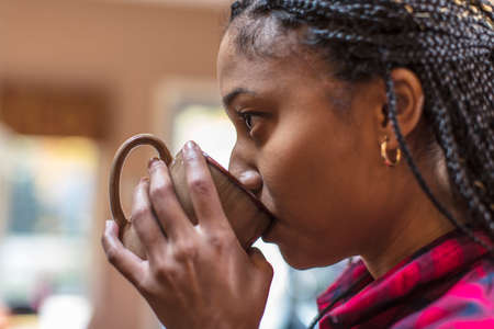 Close up of mid adult woman in kitchen drinking coffee