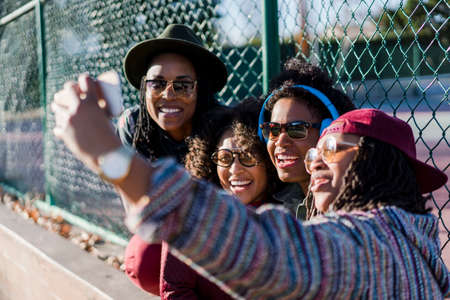 Group of female friends taking self portrait using smartphoneの写真素材