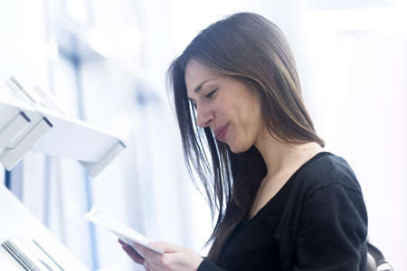 Side view of woman holding paperwork looking down smilingの写真素材