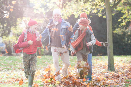 Family having fun in park, walking through autumn leavesの写真素材