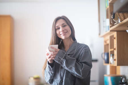 Young woman at home, holding hot drinkの写真素材