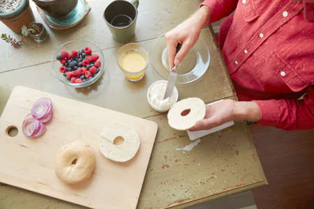 Overhead view of man spreading soft cheese on bagelの写真素材