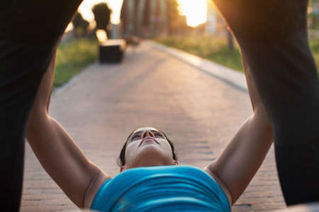 Woman training between personal trainers legs on sidewalkの写真素材
