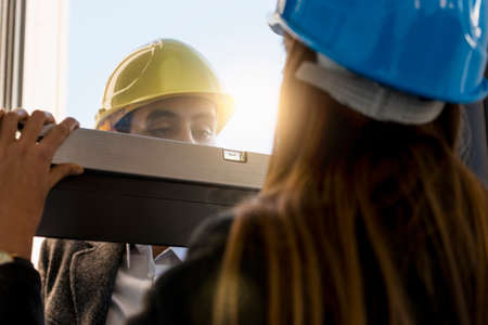 Architect and businesswoman wearing hard hats  inspecting new office window
