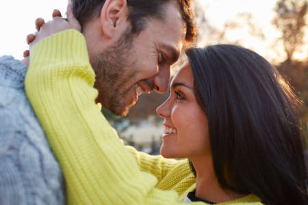 Woman with arms around man face to face smiling