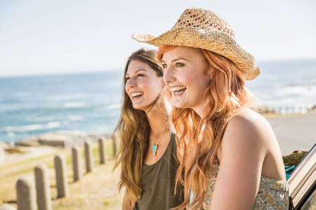 Two mid adult female friends looking out from coast road, Cape Town, South Africa