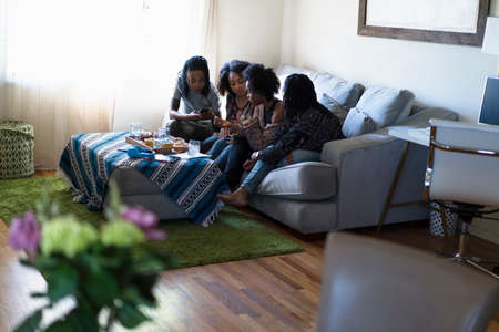 Four female friends relaxing at homeの写真素材
