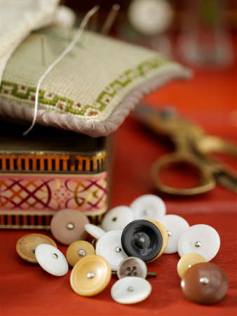 Vintage buttons and pin cushion on red tableの写真素材
