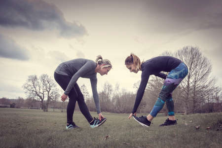 Side view of women in field bending forward touching toesの写真素材
