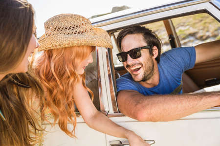 Two women flirting with man at car window on coast road, Cape Town, South Africa
