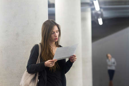 Woman in front of columns looking at paperwork
