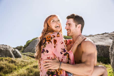 Couple outdoors, woman sitting on man's lap, face to faceの写真素材