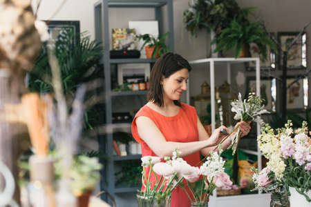 Florist arranging bouquet in flower shop, smilingの写真素材