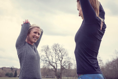 Women face to face, hands behind head stretchingの写真素材