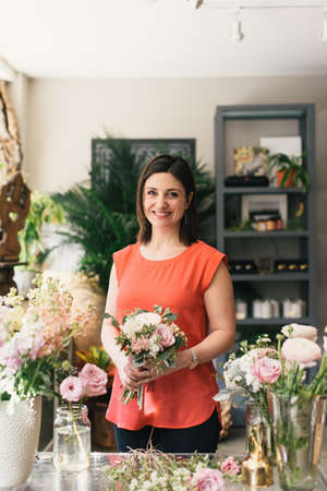 Portrait of florist in flower shop, holding bouquet, smilingの写真素材