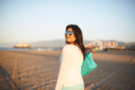 Woman looking back on Santa Monica beach at sunset, California, USAの写真素材