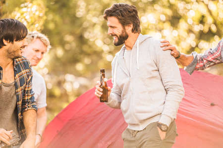 Four men drinking beer whilst camping  in forest, Deer Park, Cape Town, South Africa