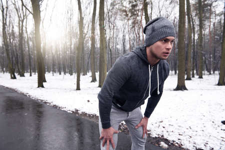 Young man exercising in snowy forestの写真素材