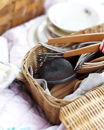 Close up of kitchen utensils and cutlery in wicker picnic basketの写真素材