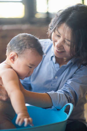 Grandmother bathing grandson in tubの写真素材