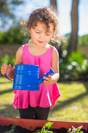 Young girl in garden, holding watering canの写真素材