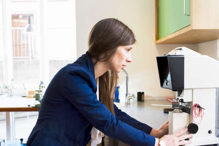 Side view of optician looking at optical equipmentの写真素材