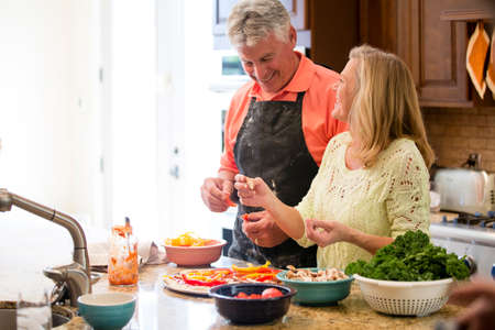 Senior couple preparing meal in kitchenの写真素材