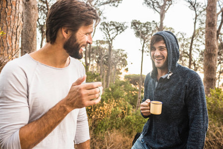 Two men drinking coffee and chatting in forest, Deer Park, Cape Town, South Africaの写真素材