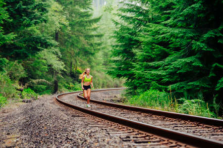 Teenage girl running along rural train track