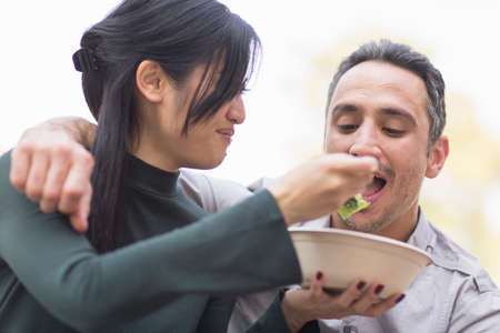 Woman feeding man salad
