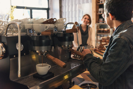 Waiter heating milk jug at coffee machine in cafeの写真素材