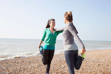 Two women training, standing on one leg on Brighton beachの写真素材