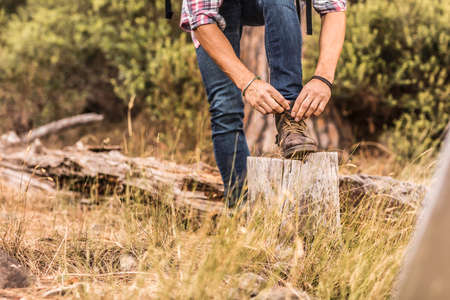 Waist down view of male hiker tying hiking boot laces, Deer Park, Cape Town, South Africaの写真素材