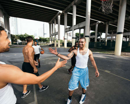 Young men on basketball court connecting with handshake after basketball game smilingの写真素材